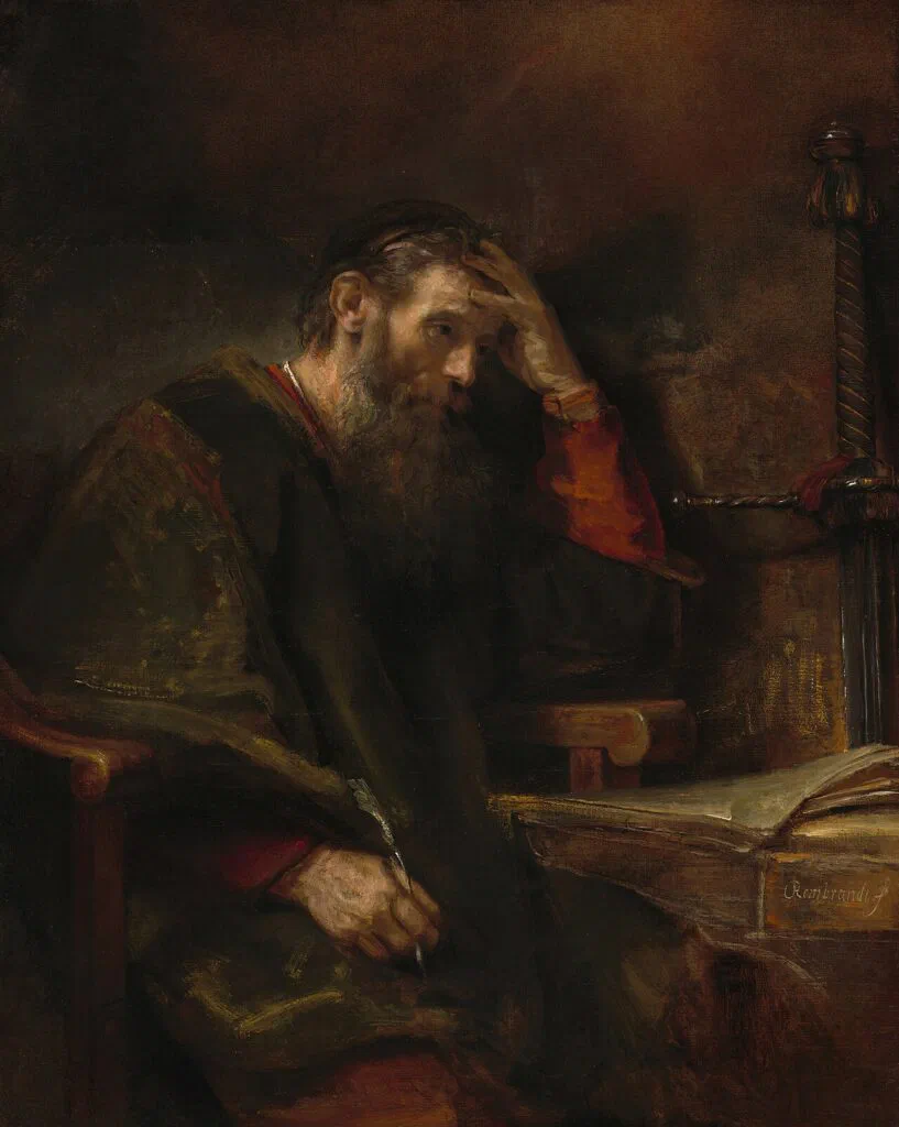 Rembrandt's oil painting of the Apostle Paul, an aging bearded man in scholarly robes seated at his writing desk with a quill and a sword propped beside him.