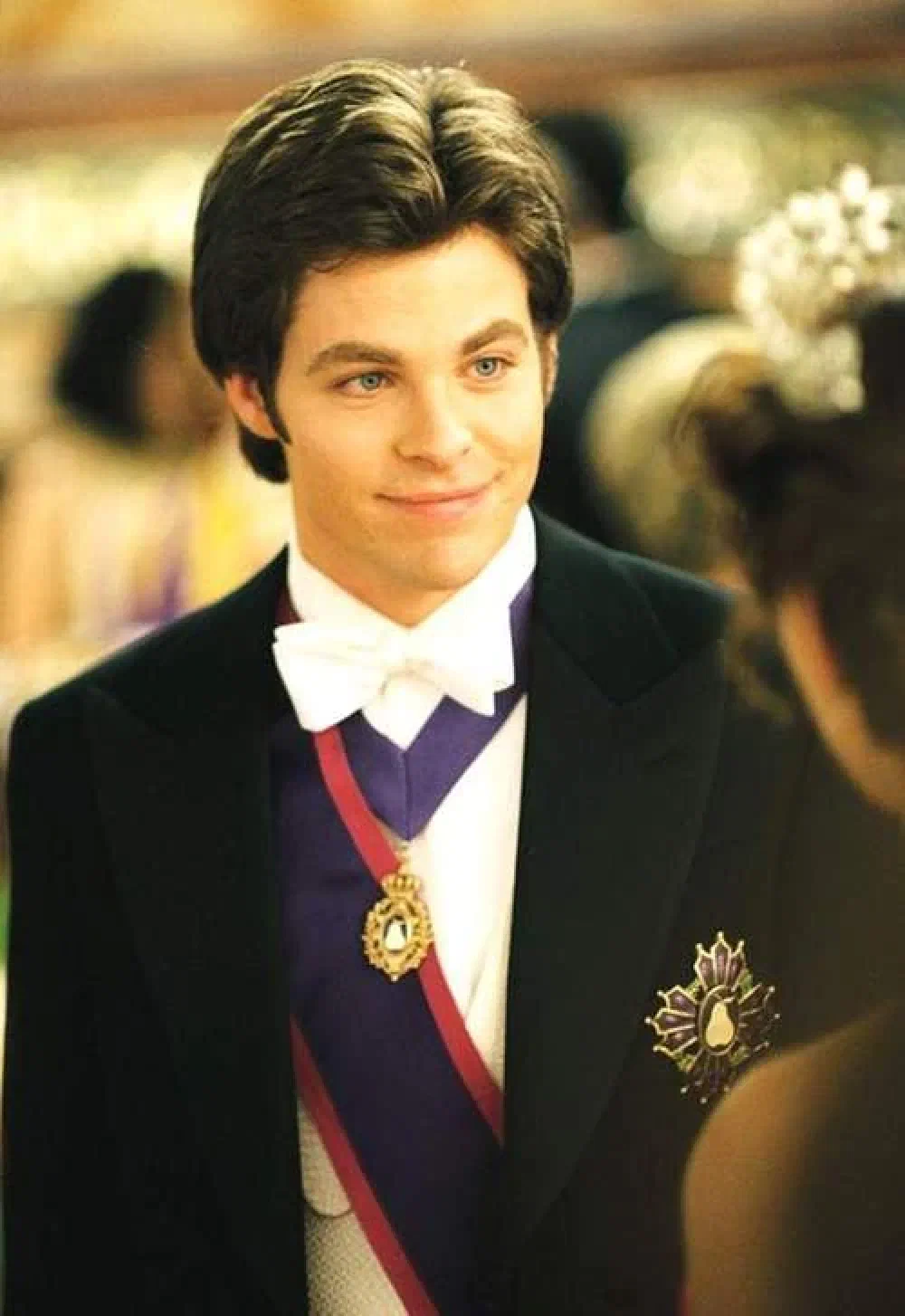Chris Pine as Lord Nicholas Devereaux in Princess Diaries 2, wearing a black tailcoat, white bowtie, and a Genovian sash with a jeweled medallion.