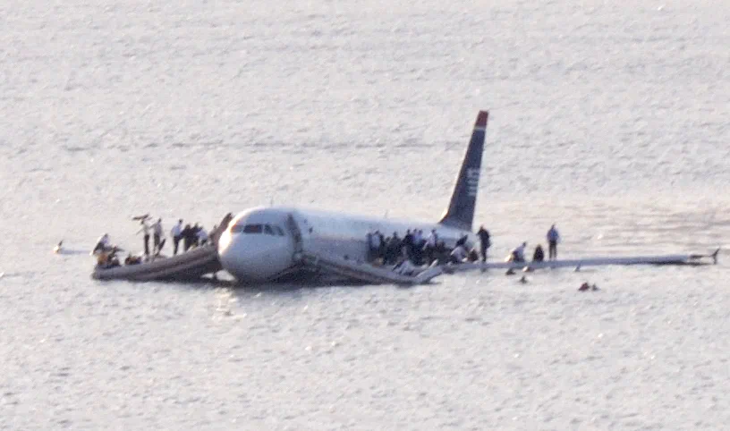 US Airways Flight 1549 floating in the Hudson River after Captain Sully&rsquo;s emergency water landing, with passengers standing on the wings awaiting rescue.
