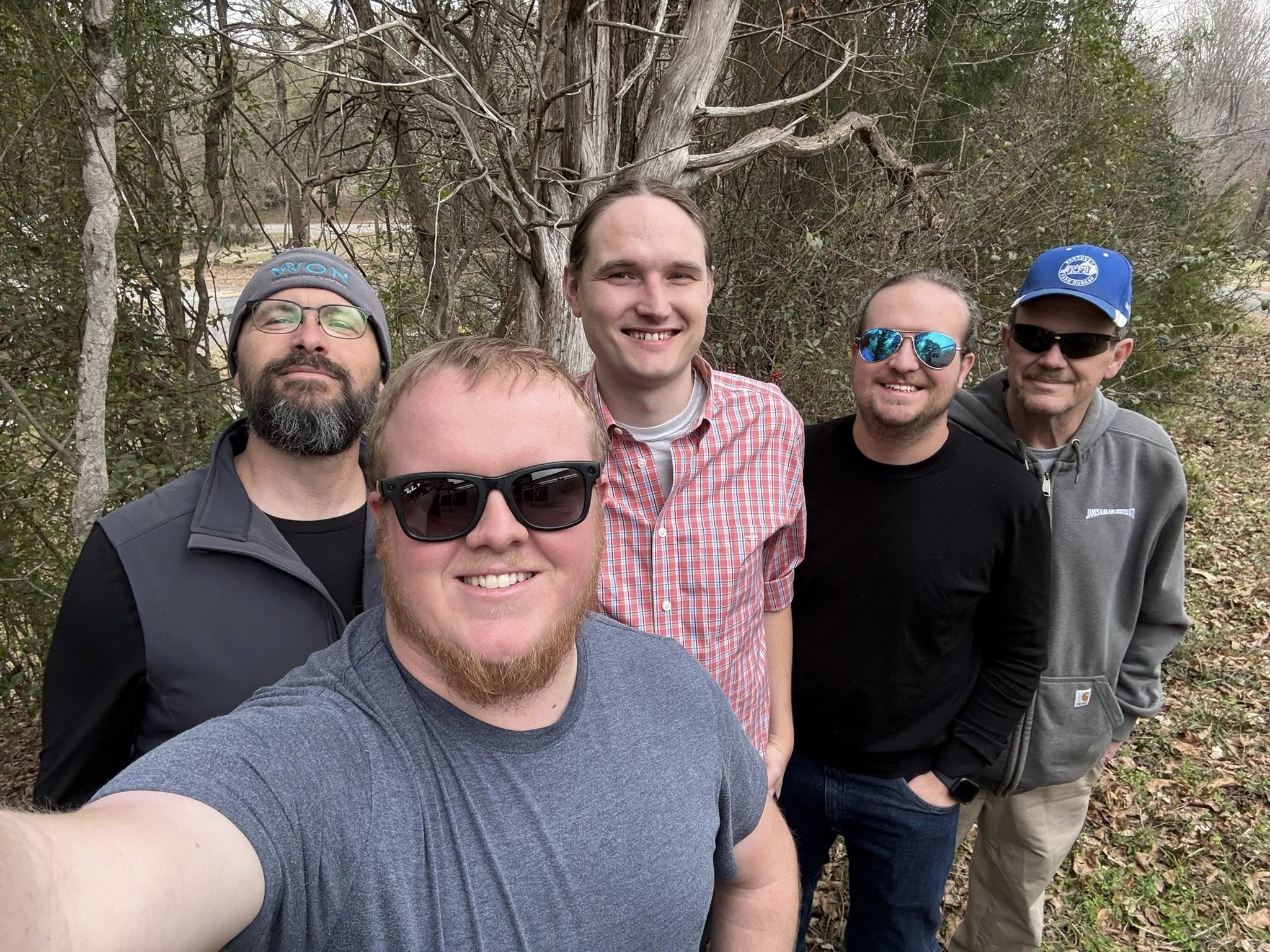 Outdoor selfie of five men, the Centreville Tech and Alabama Lightwave team, smiling in front of a stand of bare winter trees.